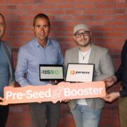 Four men in front of a red brick wall.