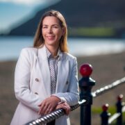 Woman in white jacket beside the sea.