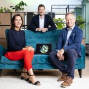 Woman and two men sitting around a blue couch.