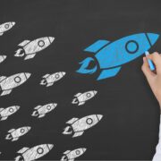 Big blue rocket and white rockets drawn on a blackboard.