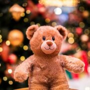 A cute teddy bear in front of a Christmas tree.