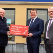 Three men, two holding a red box.