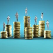 Finance professionals standing on stacks of coins.