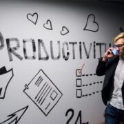 Employee on phone walking by a wall with 'Productivity' emblazoned on it.