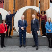 Students and business people in front of a DCU sculpture.