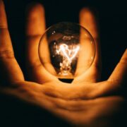 A hand holding a lightbulb in palm.