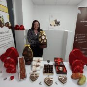 Woman surrounded by chocolate products including chocolate eggs and Valentine's presents.