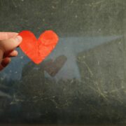 Man holding a paper heart over water.