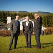 Three men standing in a field.