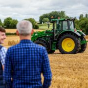 Farmers in a field in front of a tractor.