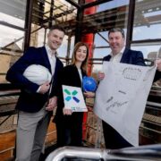 Two men and a woman holding building plans.