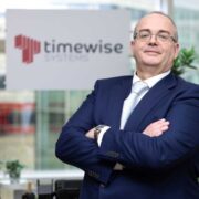 Man in navy suit with arms folded.