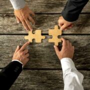 Business people using jigsaw pieces to make people fit in.