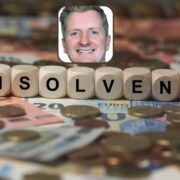Picture of man inset on scrabble letters spelling insolvency on top of euro cash and coins.