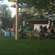 People enjoying an outdoor festival surrounded by greenery.