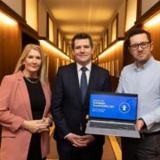 Two men and a woman holding a laptop with words EU Accessibility Act on screen.