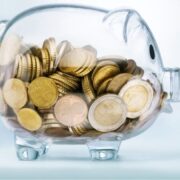 Transparent piggy bank filled with euro coins.