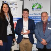 A woman and two men at an awards ceremony.