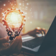 Person holding lightbulb while working on a computer.