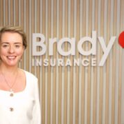 Woman in white blouse in front of a sign saying Brady Insurance.