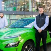 Four men standing around a green Hyundai car.
