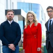 Two men and a woman in a red dress.