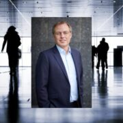 Man inset on image of people walking down a large corridor.