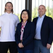 Two men and a woman standing in front of gates.
