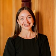 Smiling woman in black dress.