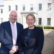Man and woman in business attire in front of a white building at UCD.