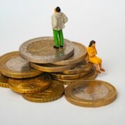 Man and woman sitting on stack of Euro coins.