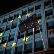 EU flag in front of a building with EU flag projected on to it.