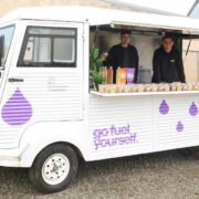 Two men inside a food truck selling drinks.