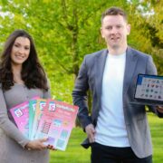 Man and woman holding a computer and learning materials.