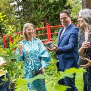 Three women and a man in a blue suit laughing in a garden.