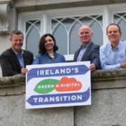 Three men and a woman on a balcony in Dun Laoghaire holding a banner proclaiming a green and digital future.