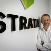 Man in white shirt leaning against a wall.