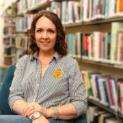 Woman in stripy blouse sitting in a library.