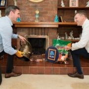 Two men lighting a fire at a fireplace using sustainable fuel.