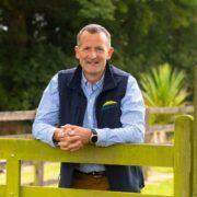Man leaning against farm gate.