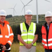 Three men in safety gear at a wind farm in Ireland.