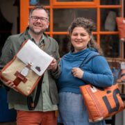 Man and woman outside a shop holding recycled leather bags.