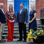 Two men and two women stand in front of a blue door.