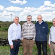 Four men in front of a wind farm.