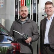 Two men standing at a forecourt.