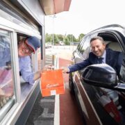 Man hands food to a driver in a car.