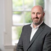Bearded man in grey suit.