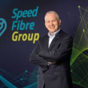 Man in navy jacket in front of a sign saying Speed Fibre Group.