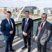 Three men on a balcony overlooking River Liffey.