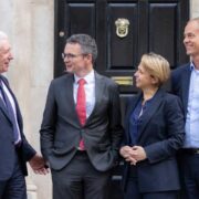 Three men and a woman speaking on the steps of a building in Dublin.